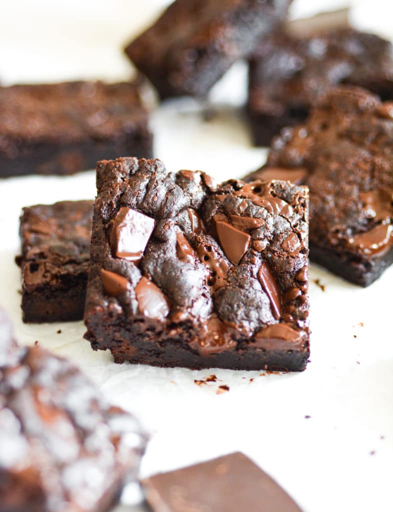Fudgy Vegan Brownies scattered on white parchement paper