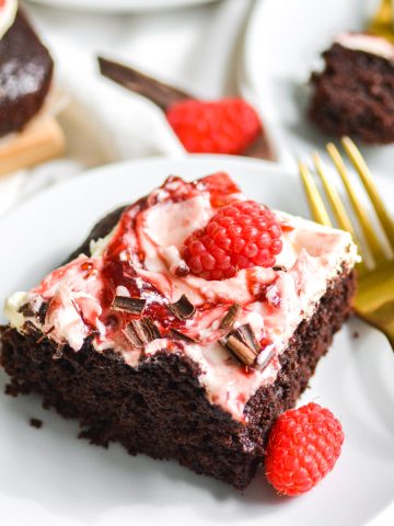 a slice of vegan gluten free chocolate raspberry sheet cake on a white plate with a gold fork