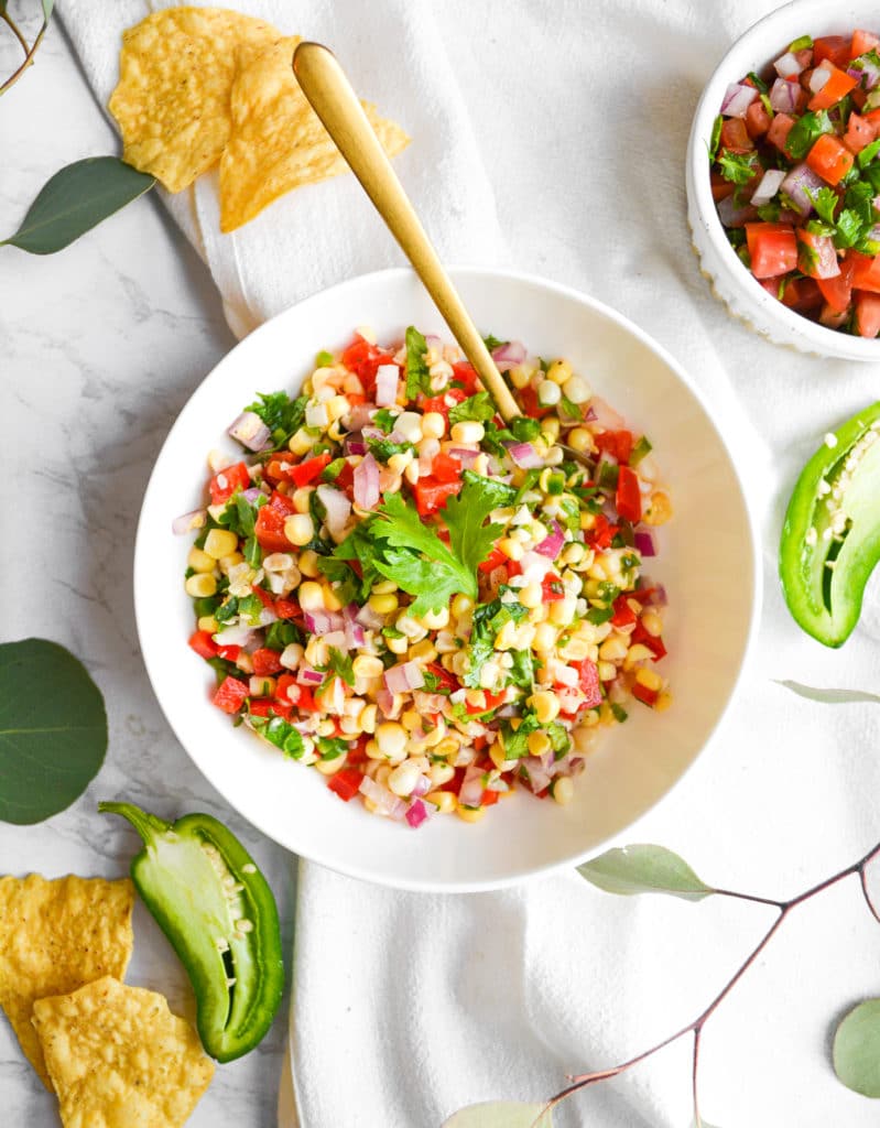 Overhead shot of Easy Corn Salsa in a white bowl with a gold spoon