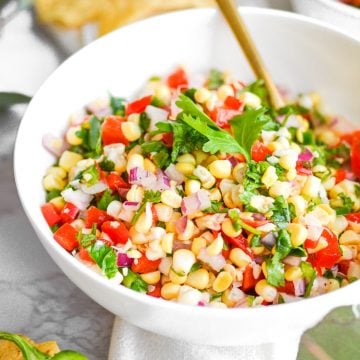 corn salsa in a white bowl on a marble board