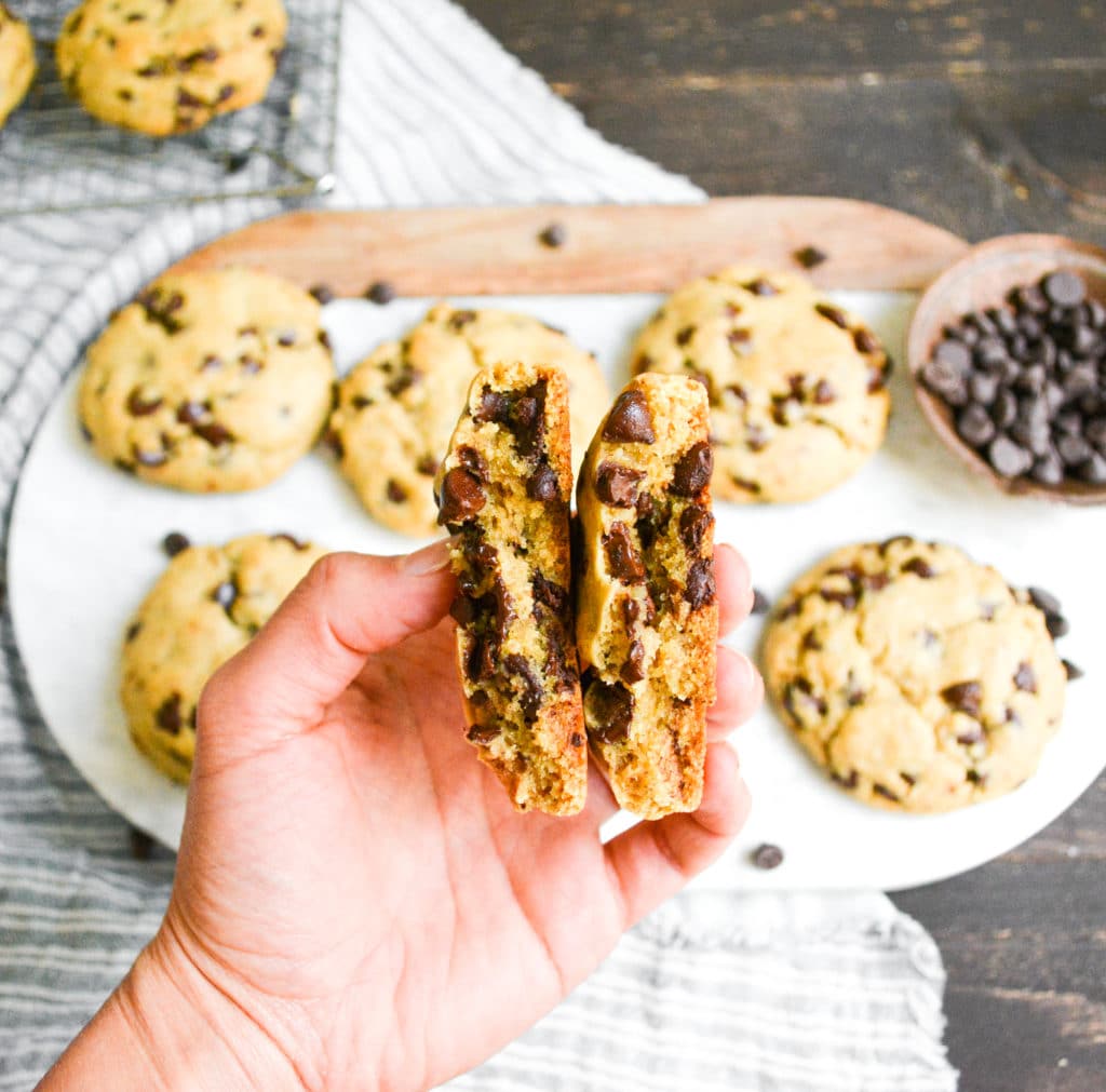 Hand holding a Vegan Levain Chocolate Chip Cookie Broken in half to show the interior
