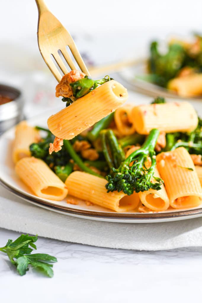 Gold fork with a bite of Rigatoni with Sausage and Broccolini on it.