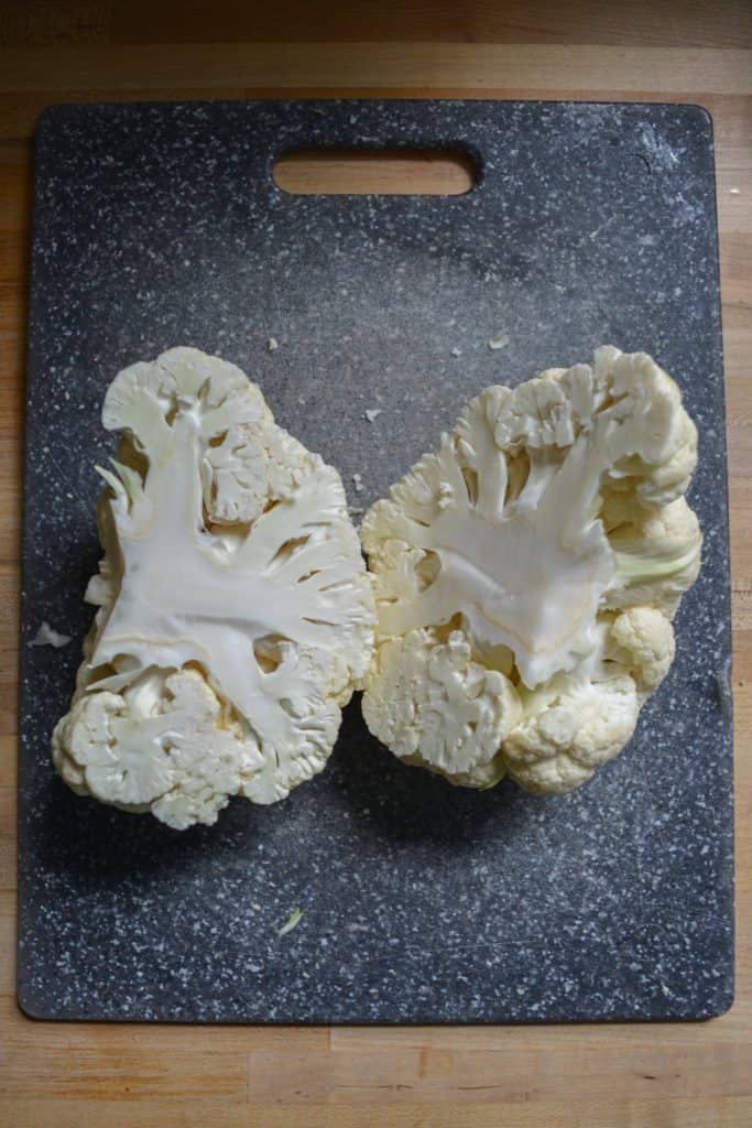 A head of cauliflower cut in half on a cutting board