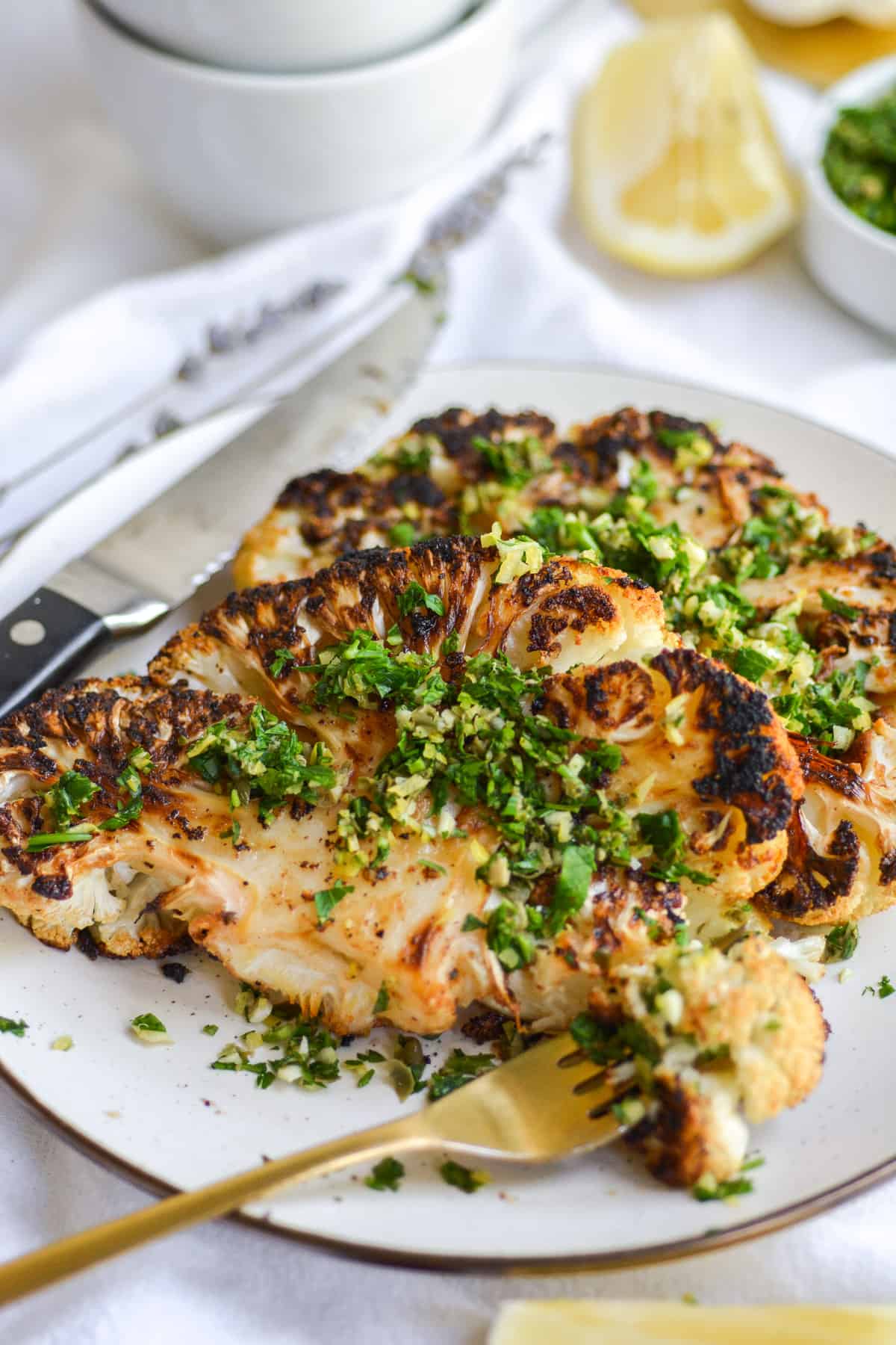 Two cauliflower steaks on a plate topped with gremolata