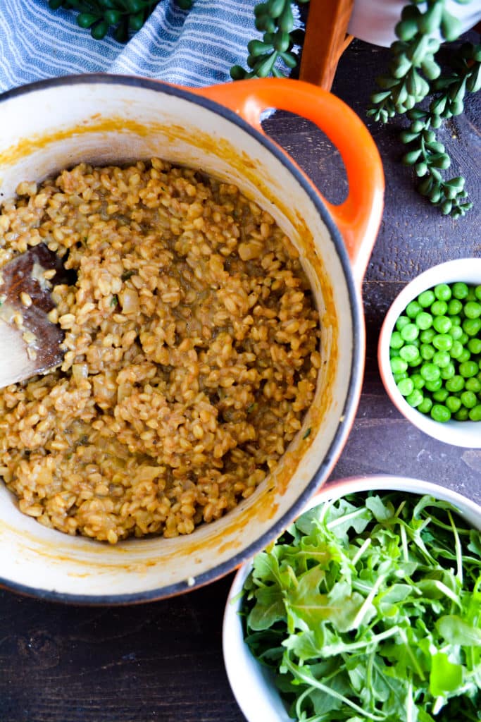 adding peas and arugula to farrotto