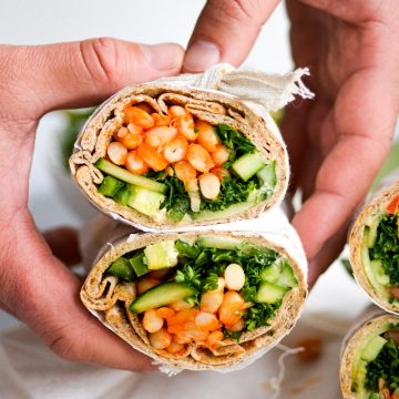 hand holding a pita filled with white bean and tabbouleh