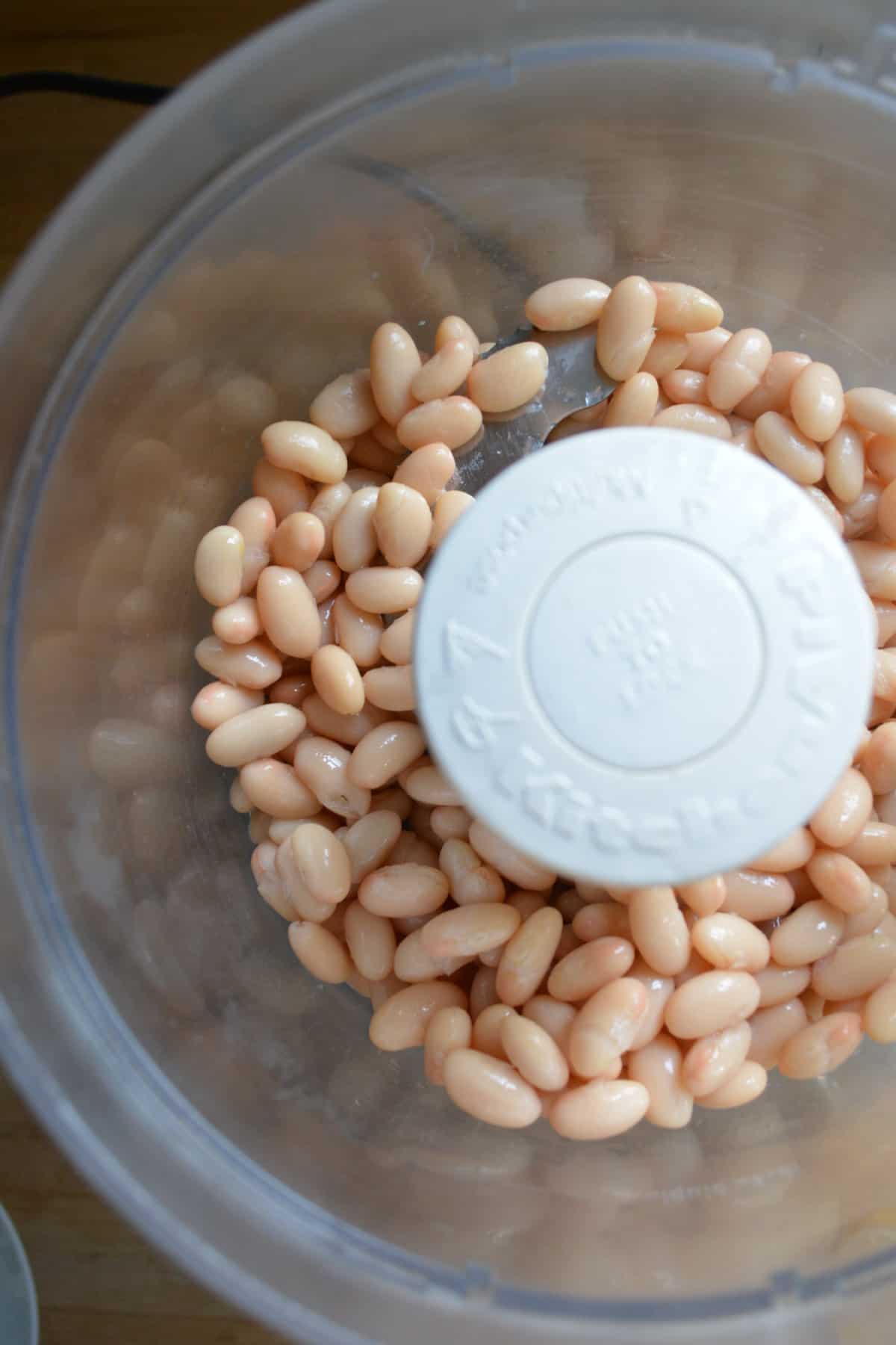 White beans in the bowl of a food processor.