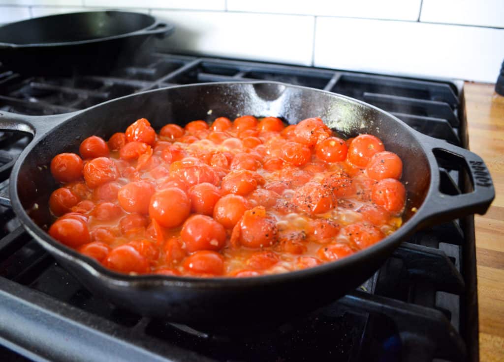 Cherry tomatoes cooking in a cast iron pan
