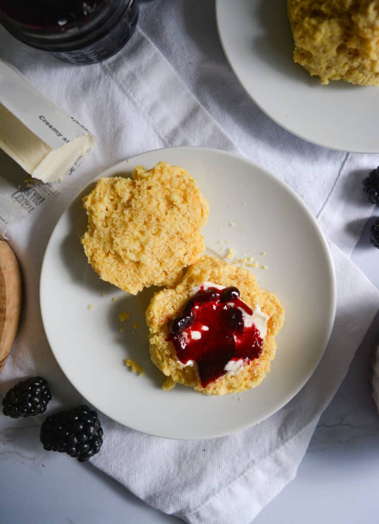 Fluffy Cornmeal Drop Biscuit on a white plate with blackberry jam