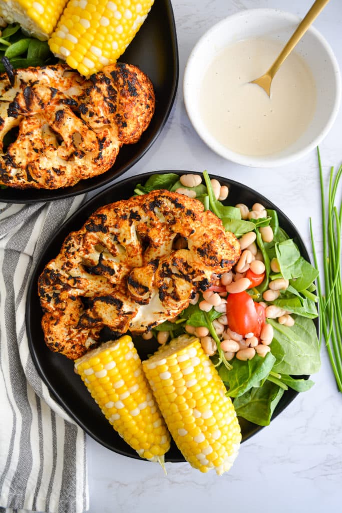 Portrait of two plates with grilled cauliflower corn and salad
