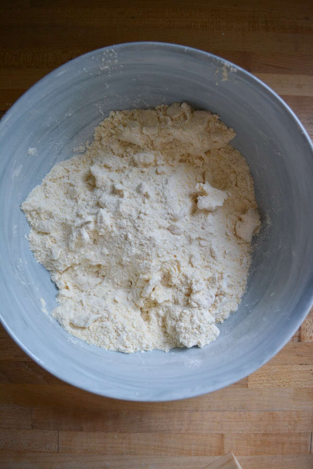 Vegan butter cut into the dry ingredients in a marble bowl