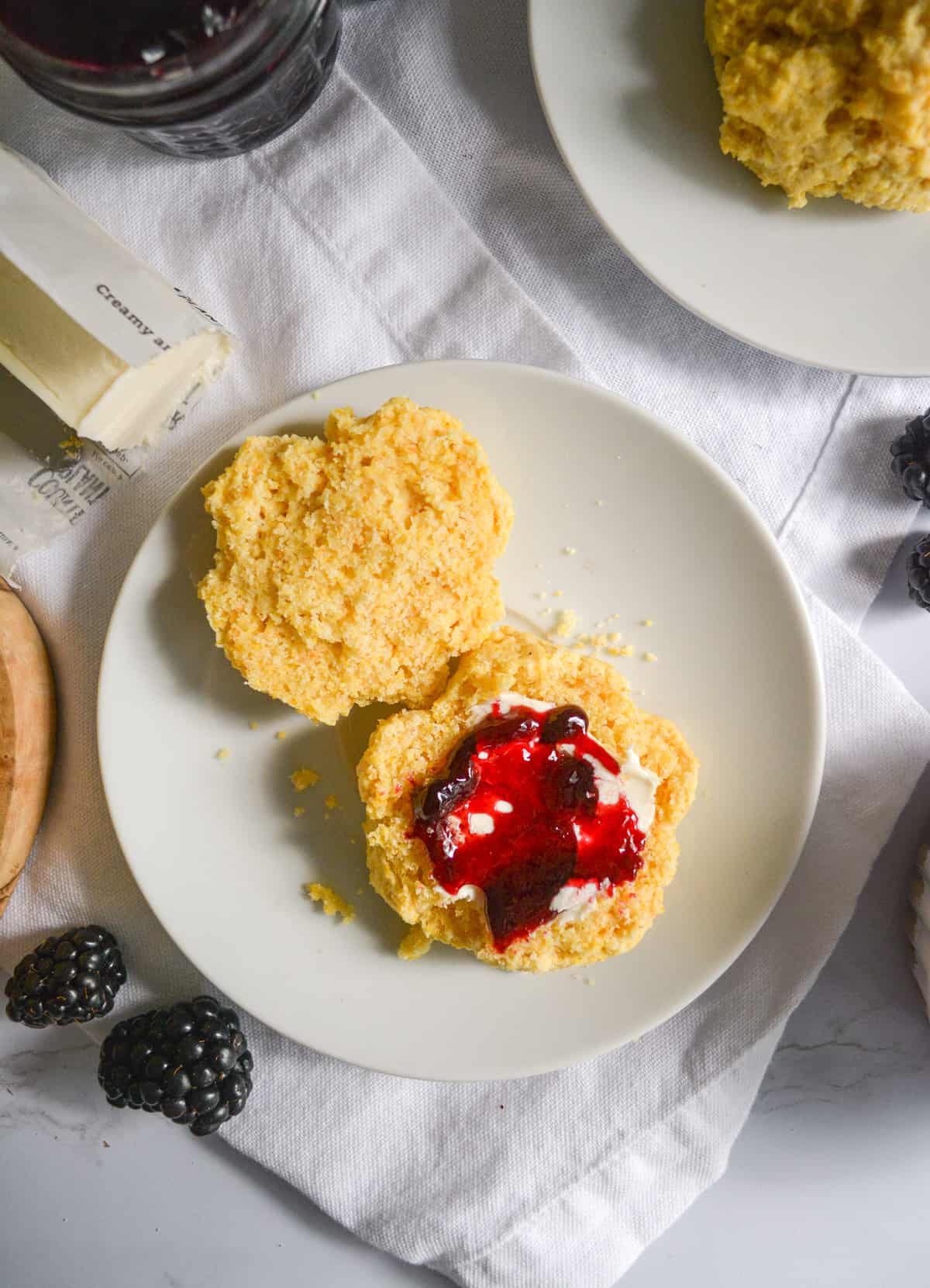 Overhead shot of a biscuit on a plate with jam and butter.