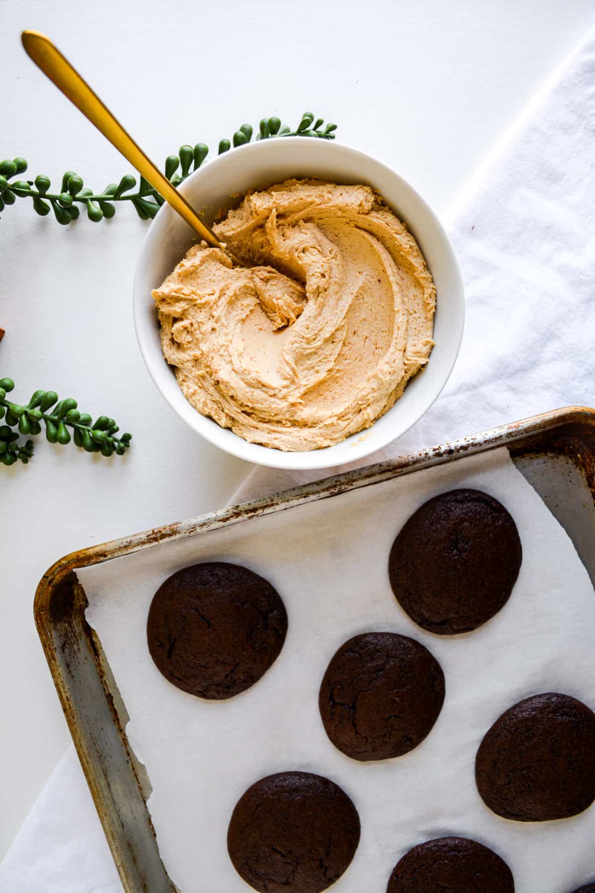 A bowl of Vegan Peanut Butter Frosting next to a tray of chocolate whoopie pies.