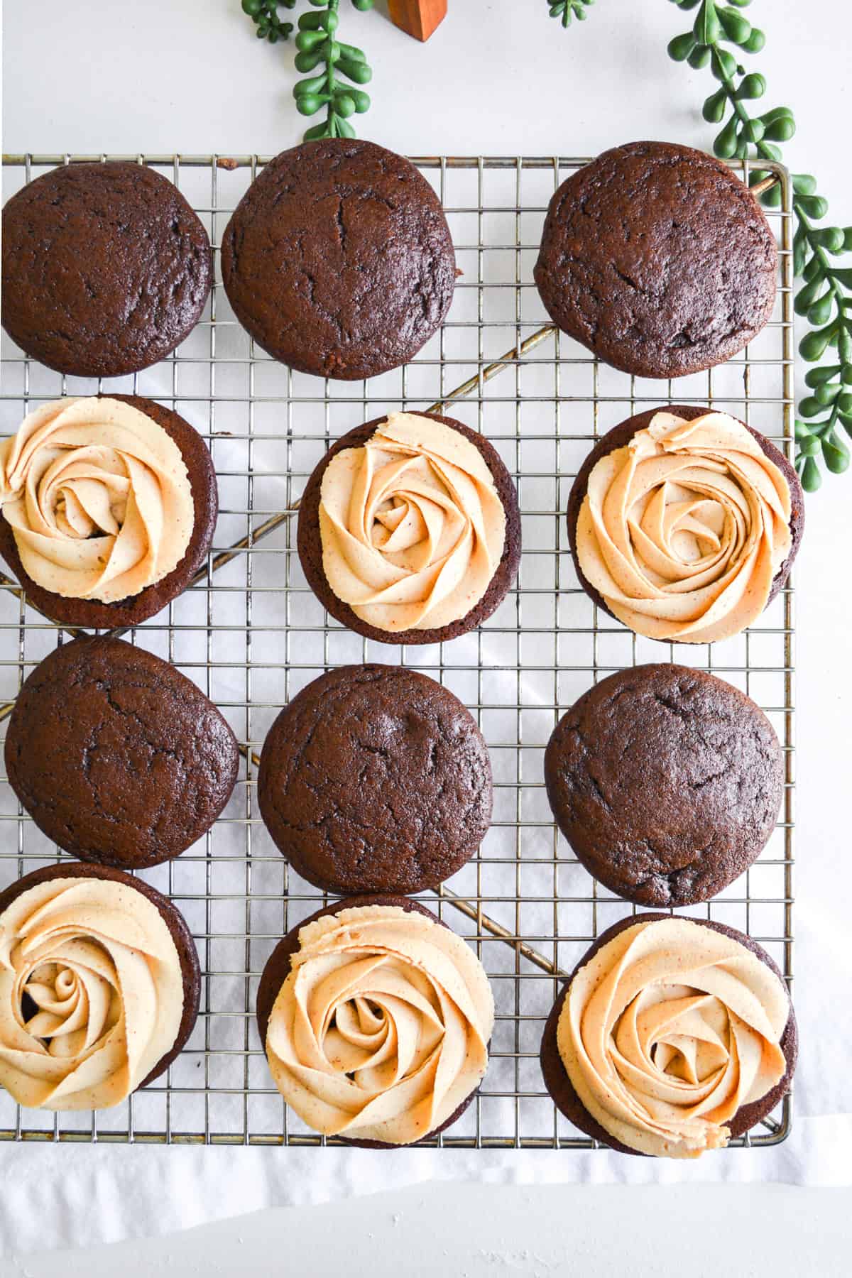 Chocolate whoopie pies with frosting rosettes on top.
