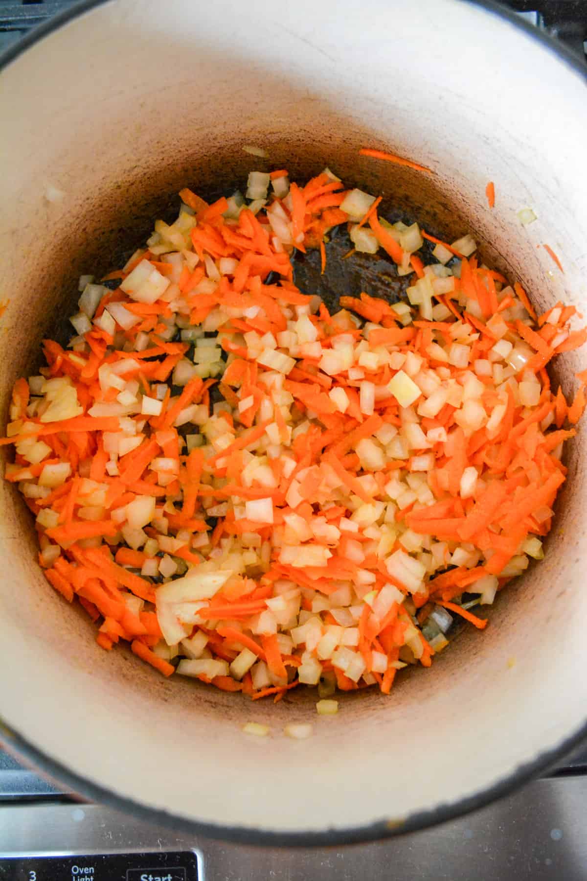 Carrots and onions sautéing in a pot.