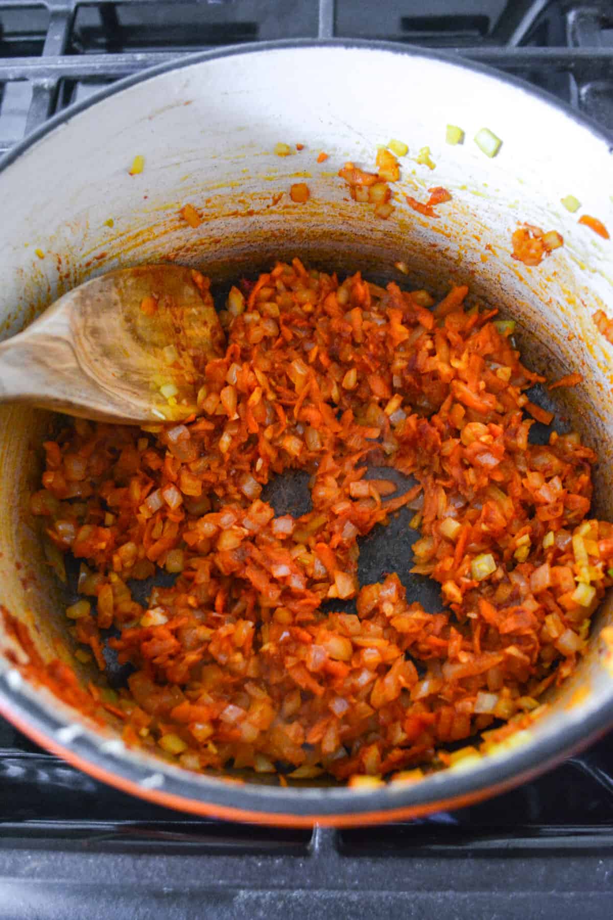 Tomato paste cooking with the onion and carrot in a pot.