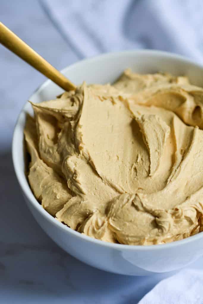 Close up of quick and simple brown sugar buttercream in a bowl with a gold spoon