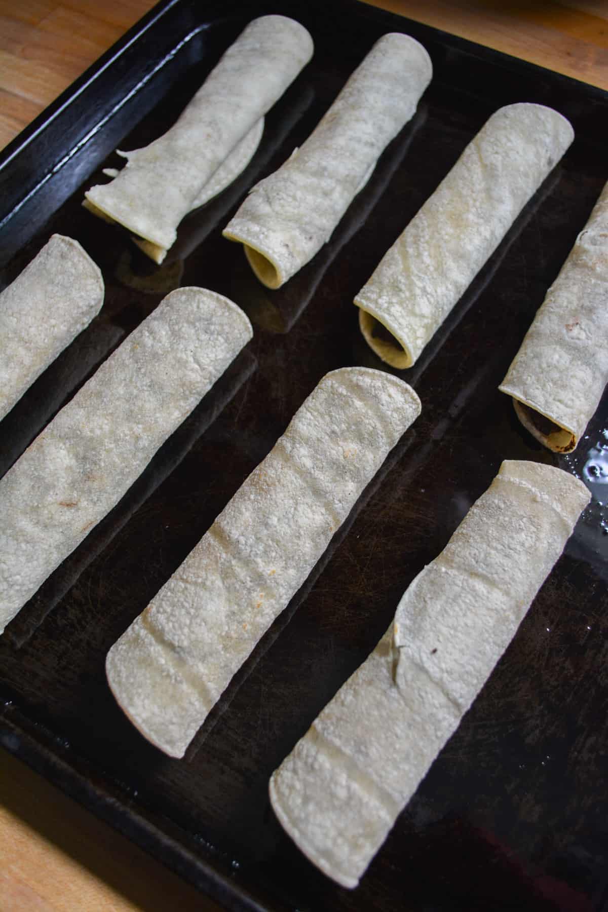 Taquitos on a baking sheet.