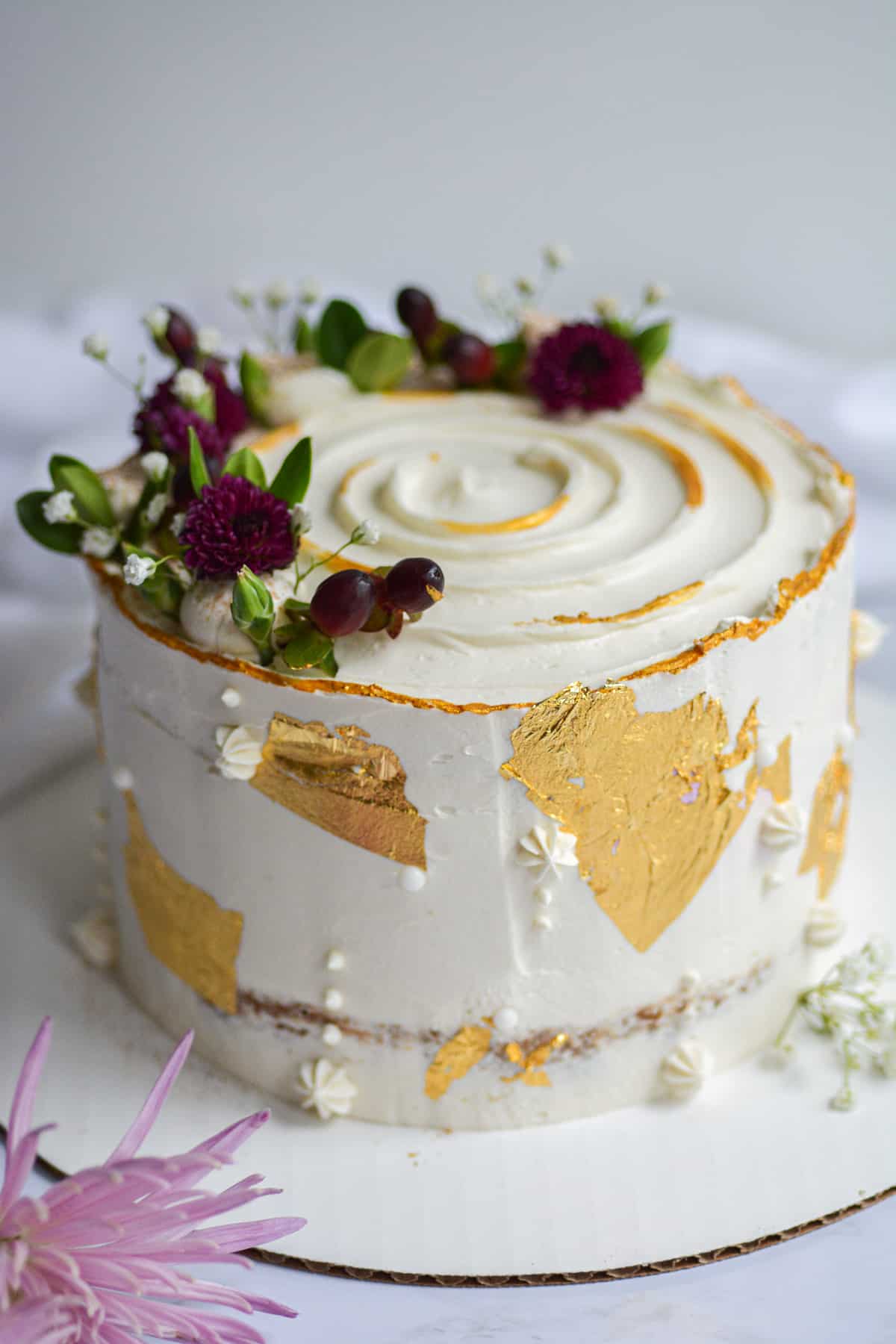 straight on shot of a frosted cake decorated with gold leaf