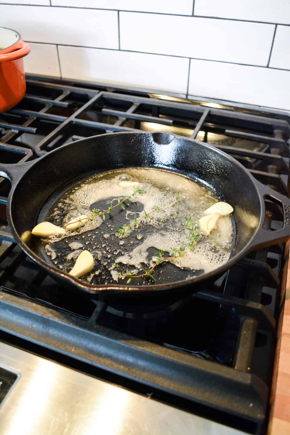 Butter, garlic and sprigs of thyme in a cast iron pan.