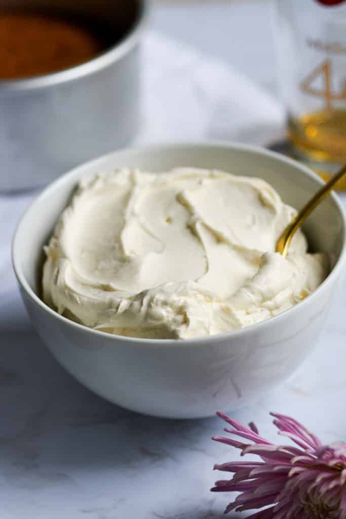 Easy Bourbon Maple Buttercream in a white bowl with a gold spoon