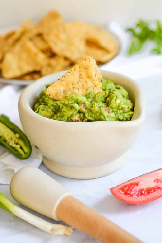 Easy and Chunky guacamole in a mortar with a tortilla chip in it