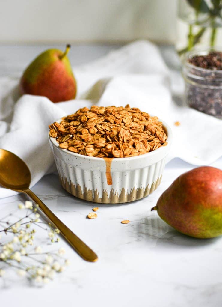 Baked vegan pear crumble in a ramekin with small red and green pears in the background