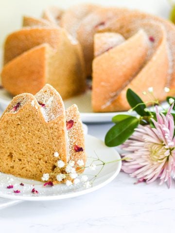 A slice of vegan earl grey bundt cake on a plate garnished with rose petals