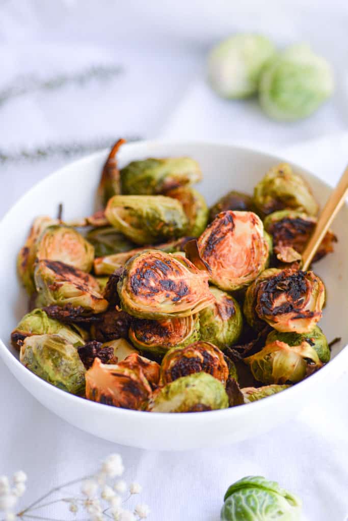Roasted Maple Dijon Brussels Sprouts in a white bowl with a gold spoon
