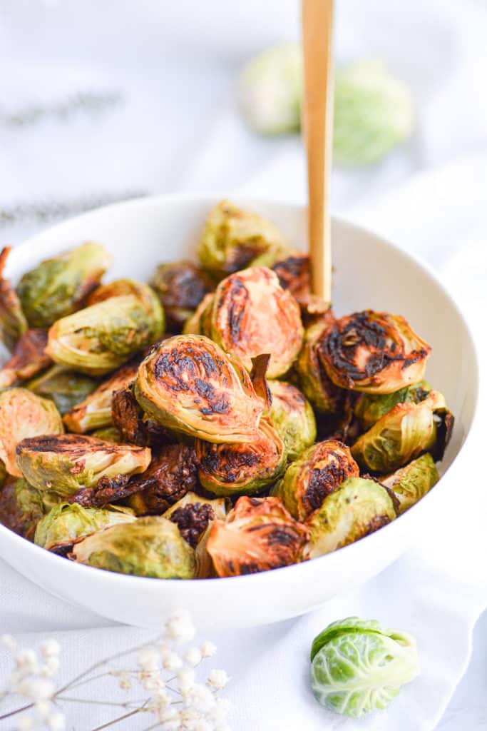 Roasted Maple Dijon Brussels Sprouts in a white bowl with a gold spoon