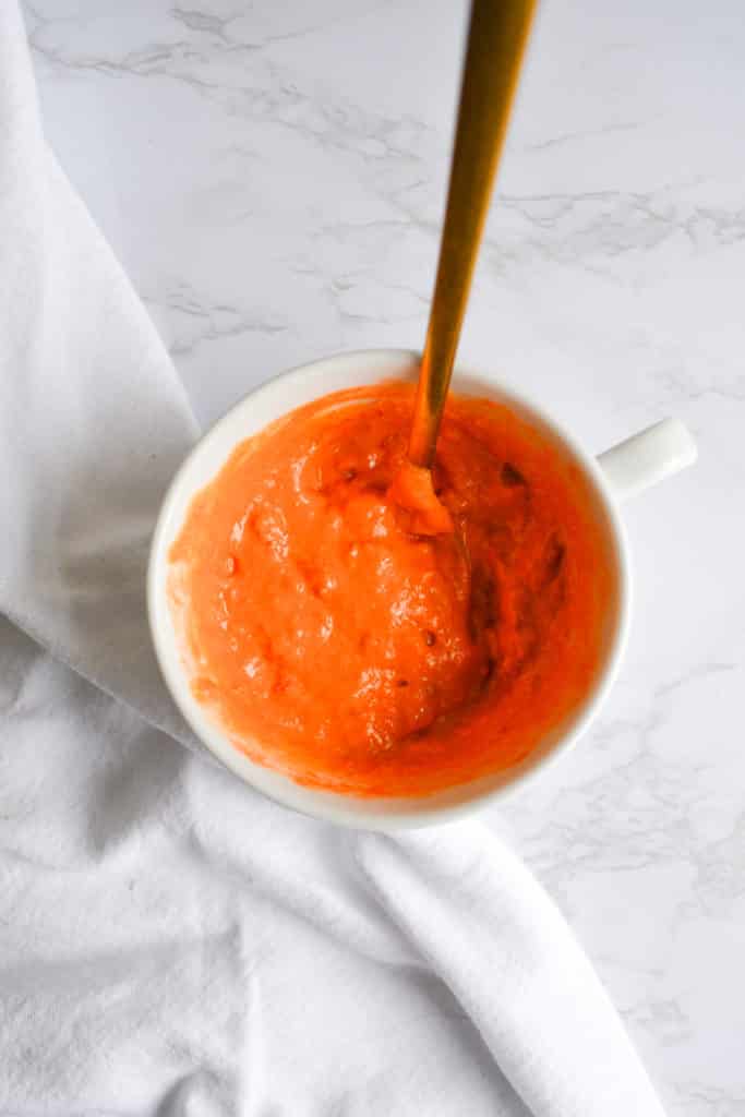 Harissa and hummus sauce in a white cup with a gold spoon