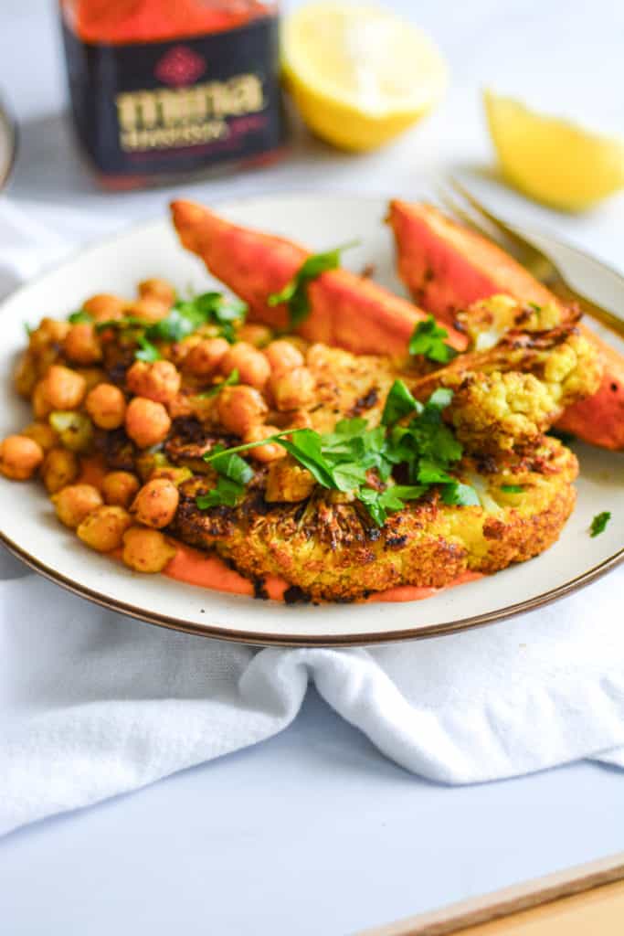 Portrait of a plate of cauliflower and sweet potato sheet pan dinner on a marble board