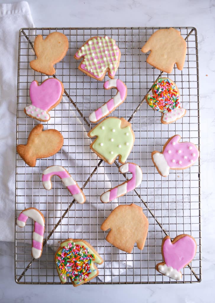 Decorated Vegan Cut-Out Holiday Cookies on a wire cooling rack over a white background