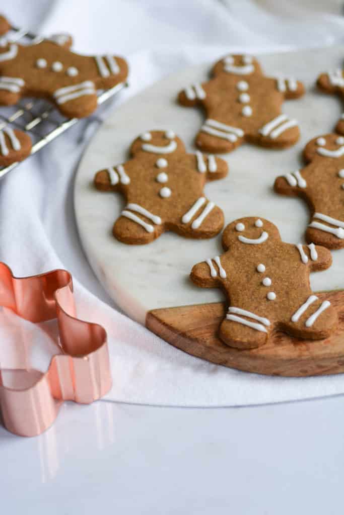 decorated gingerbread cookies on a marble cutting board next to a rose gold cookie cutter