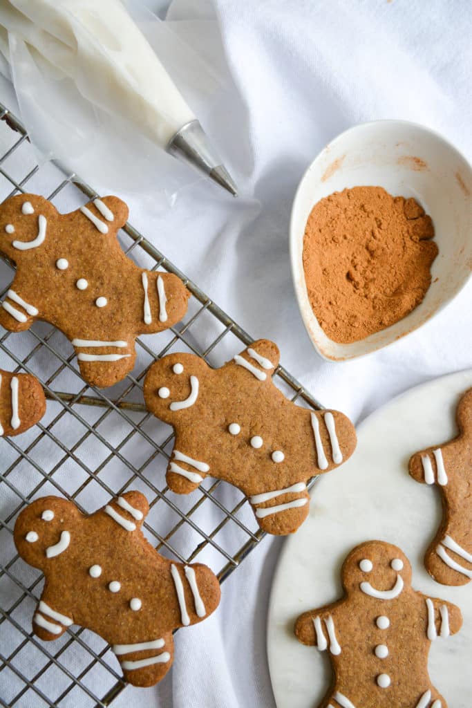 Decorated gingerbread cookies on a wire rack with a jar full of gingerbread spices