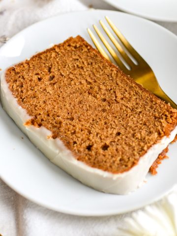 Vegan Gingerbread Loaf Cake on a white plate with a gold fork.