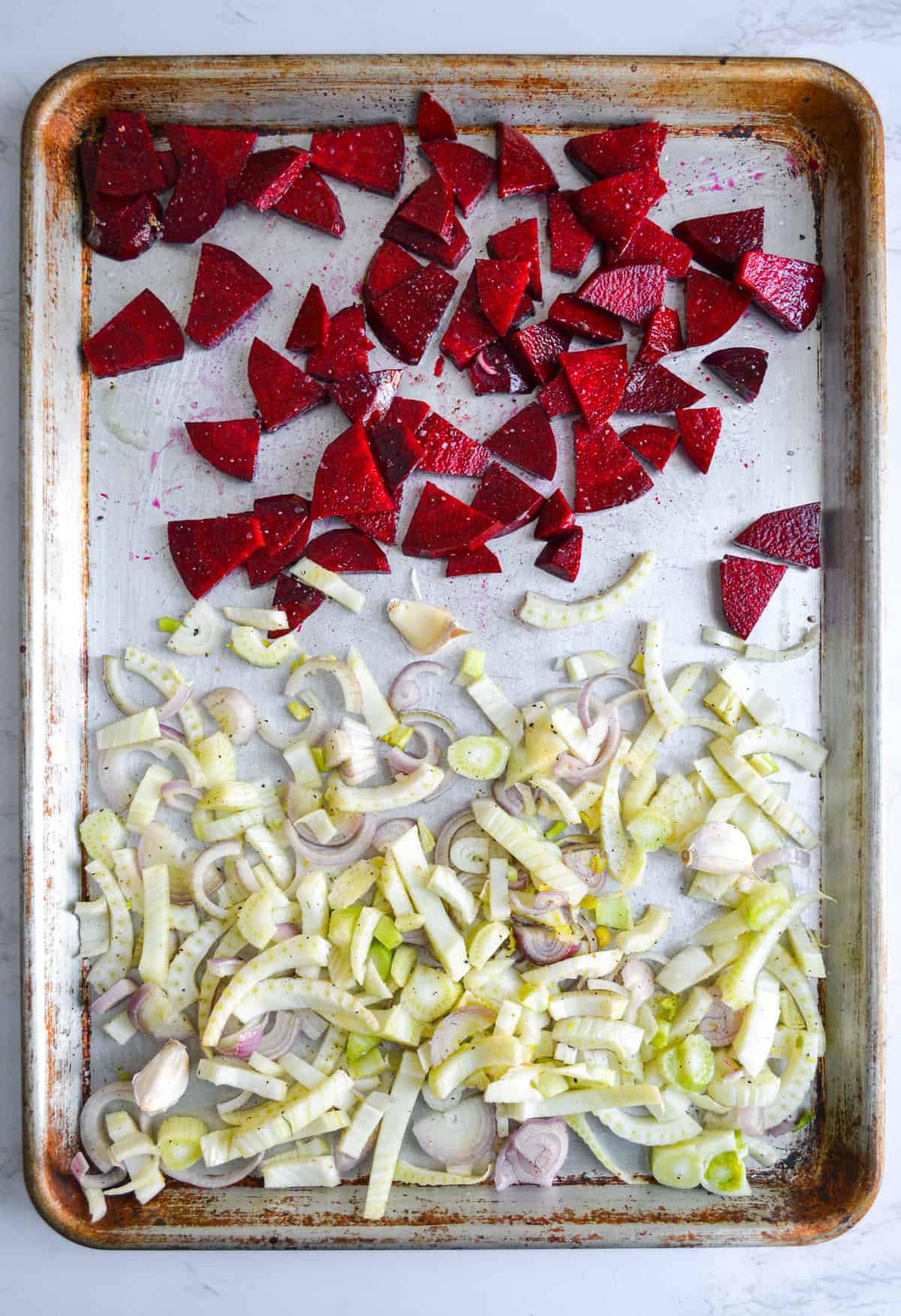 A sheet pan with chopped fennel and beets on it