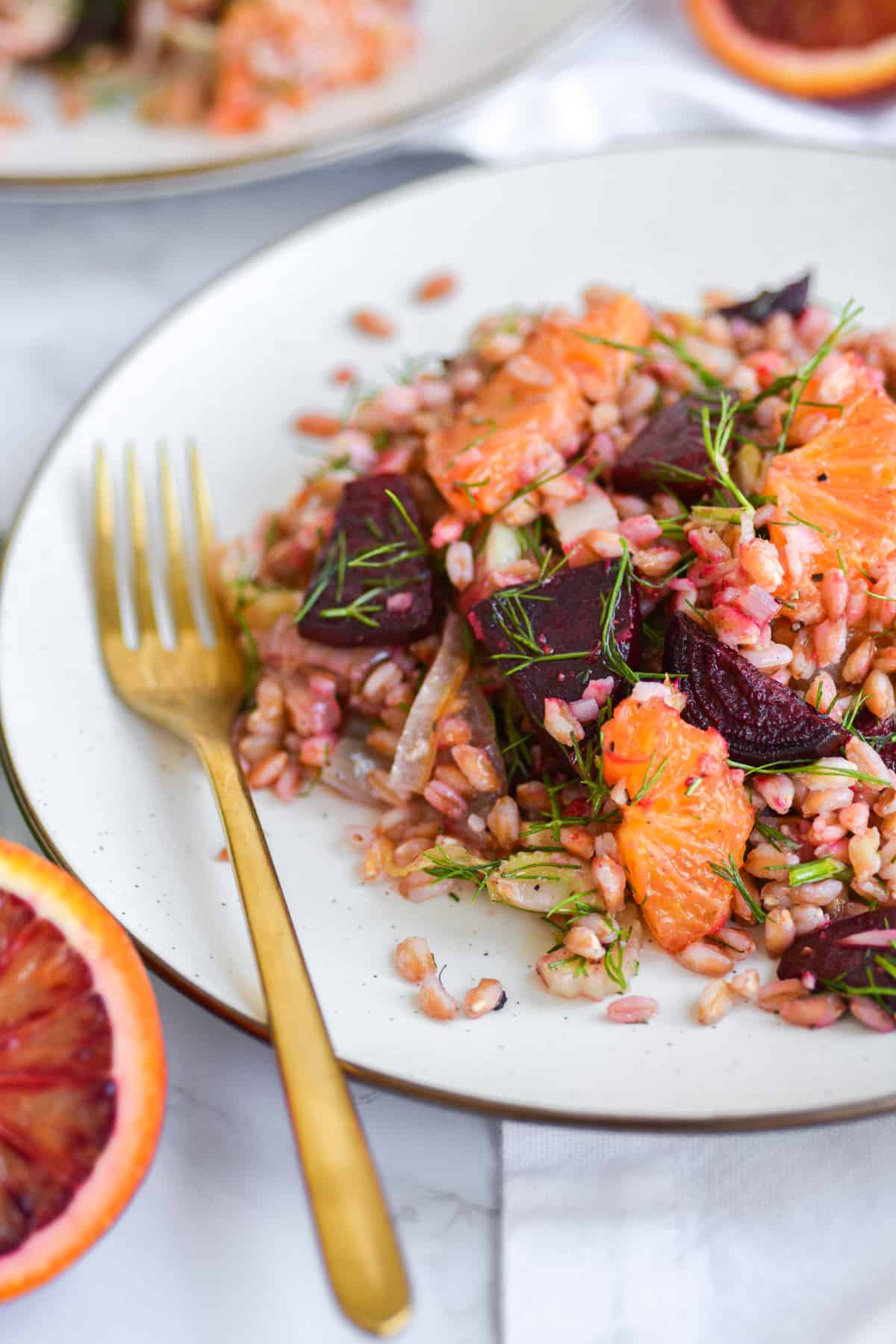 winter citrus farro salad on a plate with a gold fork