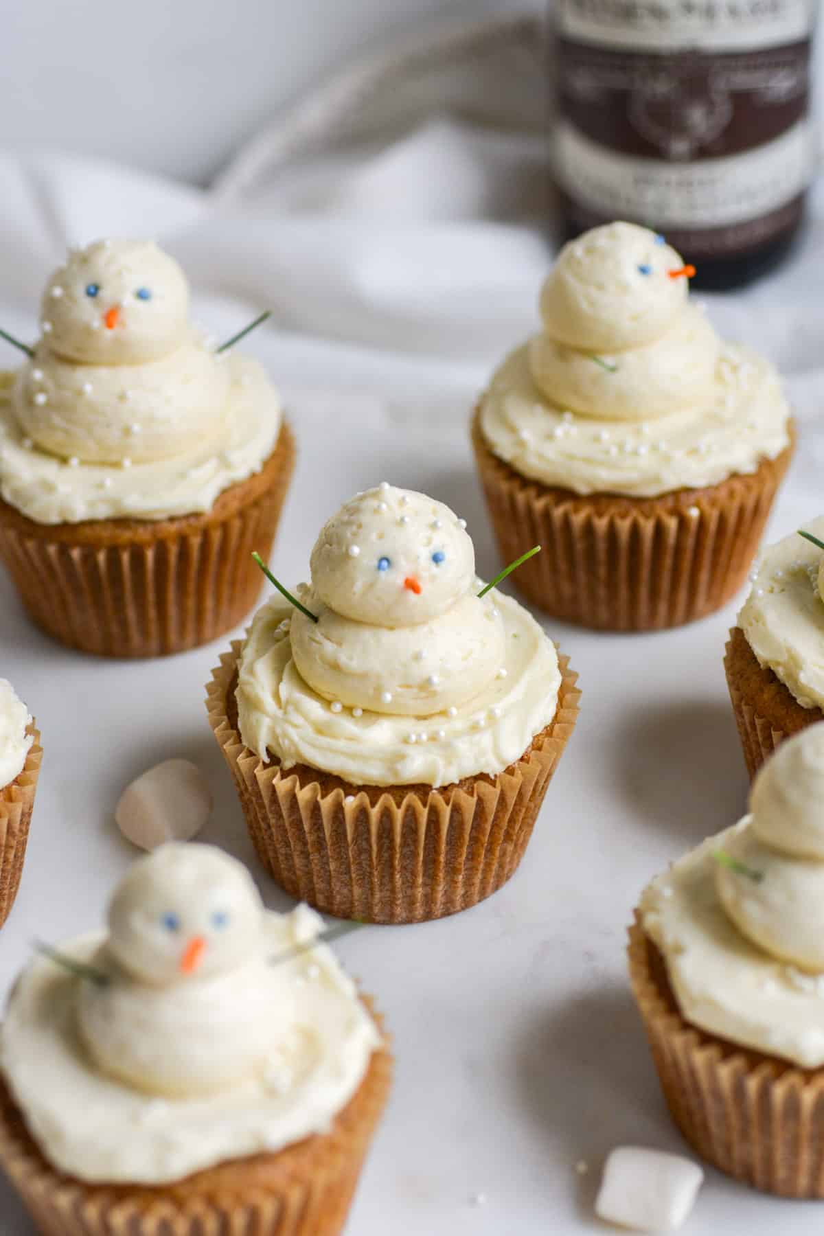 Vegan Gingerbread Cupcakes with buttercream snowmen piped on top on a marble board.