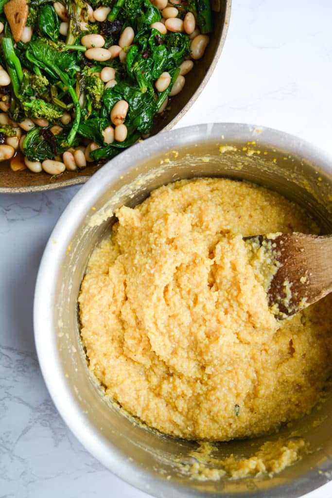 Cooked Polenta in a metal pot next to a skillet