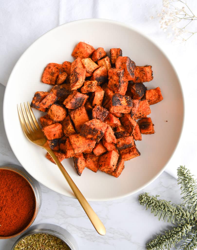 bowl with sweet potatoes next to a tin of paprika