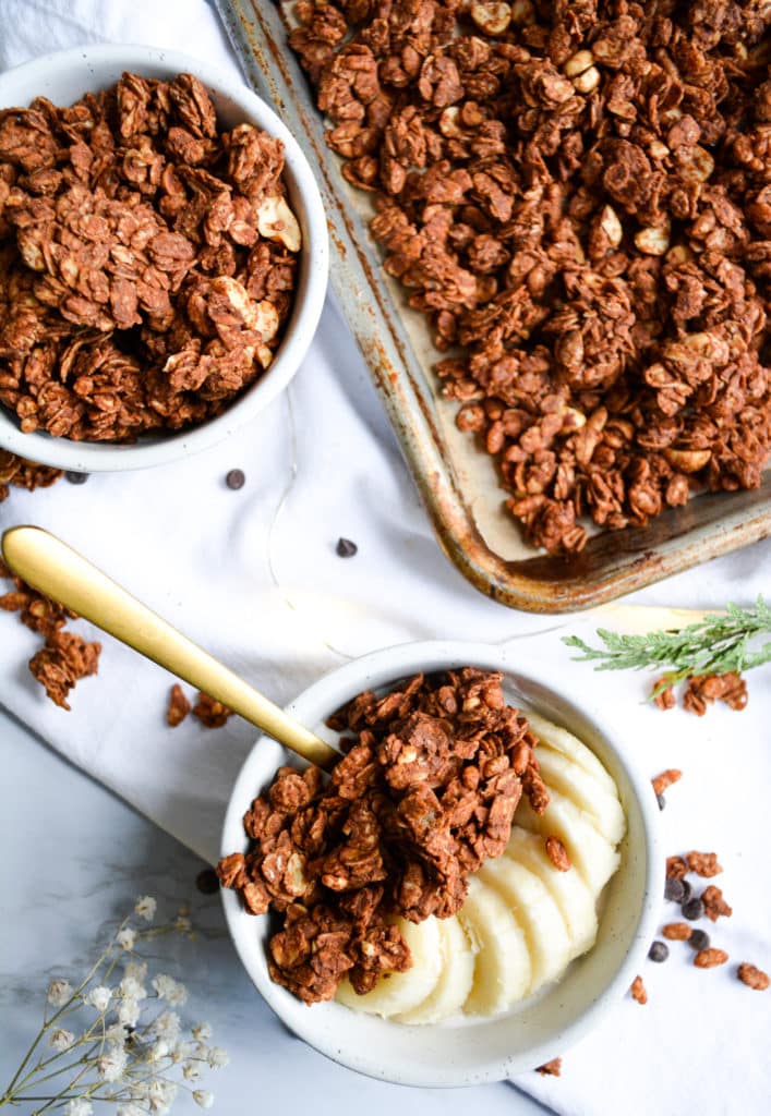 two ramekins of granola and a sheet pan with granola on it
