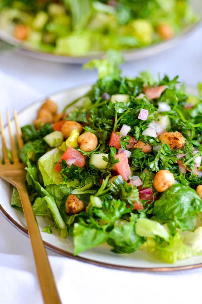 Salad with Tabbouleh on top on a tan plate with a gold fork