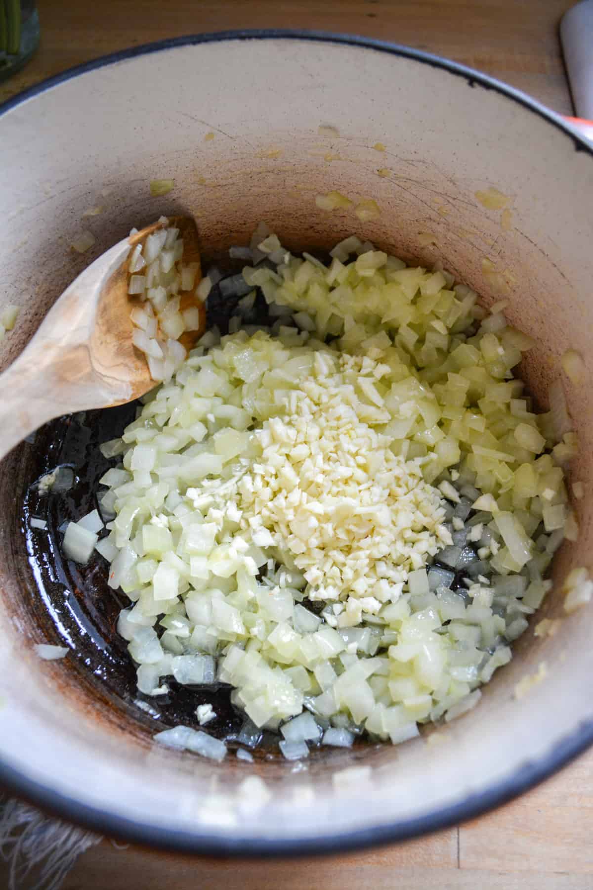 Cooked chopped onion in a pot with garlic on top.