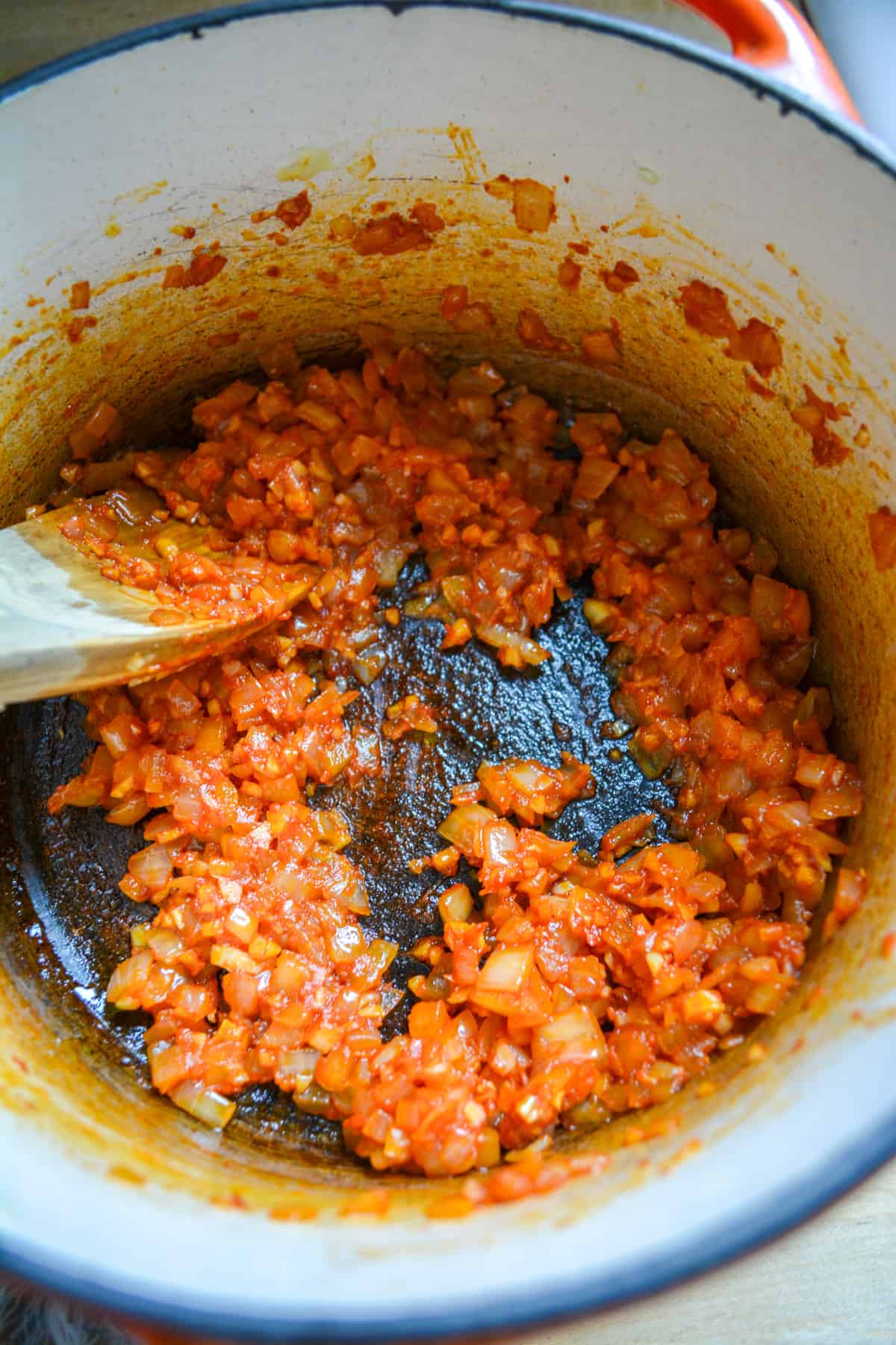 The tomato paste stirred through the onion and garlic with a wooden spoon.
