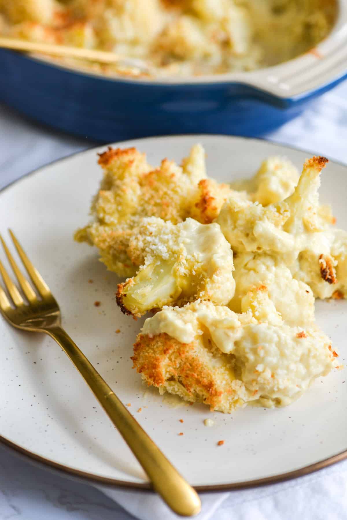 A plate of vegan baked cauliflower gratin with a gold fork