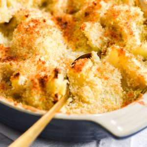 Vegan Cheesy Cauliflower Casserole in a baking dish with a gold spoon in it.