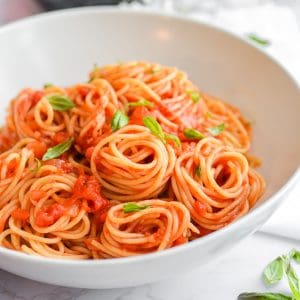 Bowl with spaghetti and sauce in it topped with basil