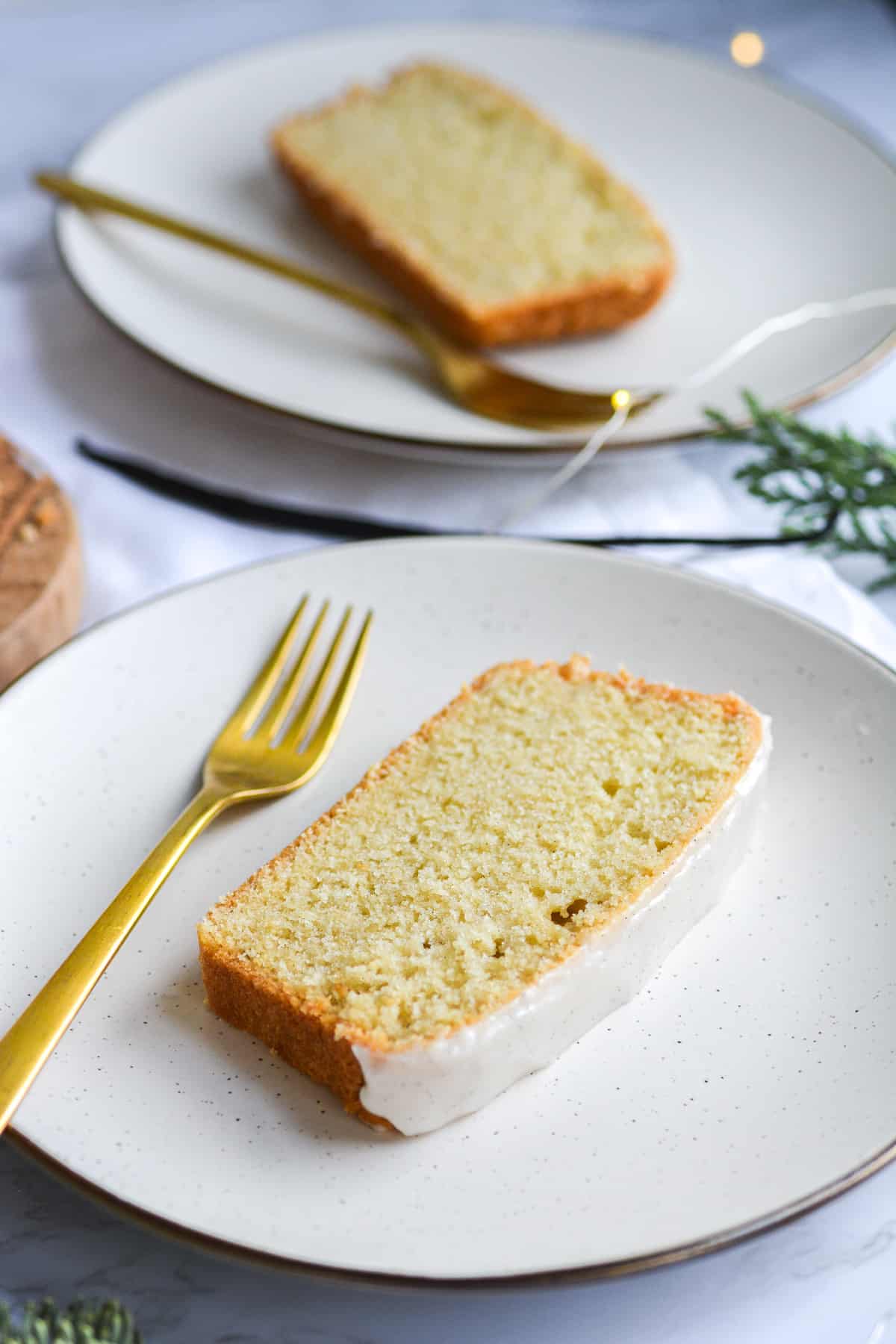 two plates with slices of vegan vanilla pound cake and gold forks