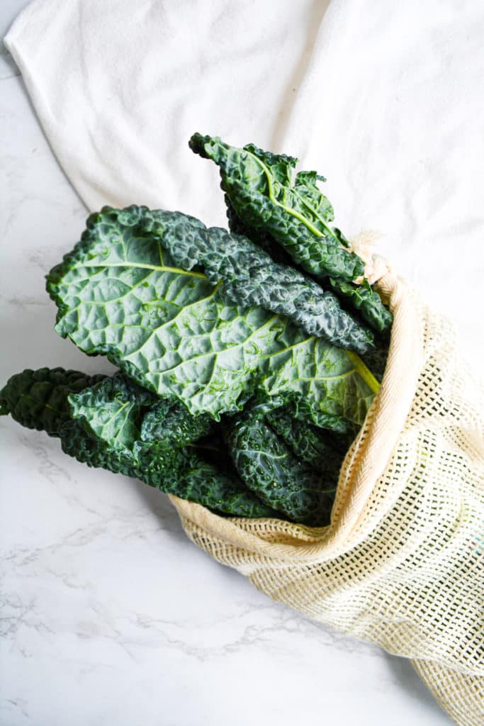 Tuscan Kale in a reusable produce bag on a marble board